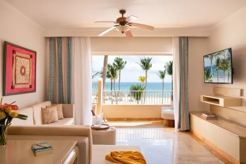 Ocean-view suite living room with sofa and balcony at Excellence Riviera Cancun.
