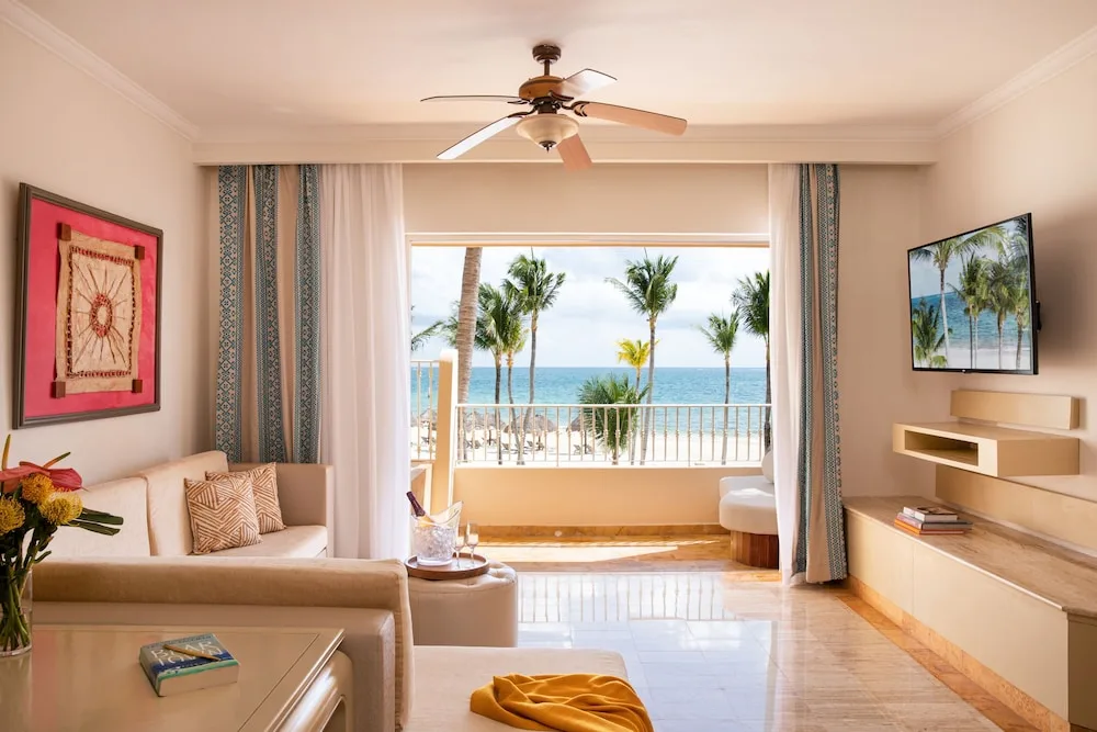 Ocean-view suite living room with sofa and balcony at Excellence Riviera Cancun.
