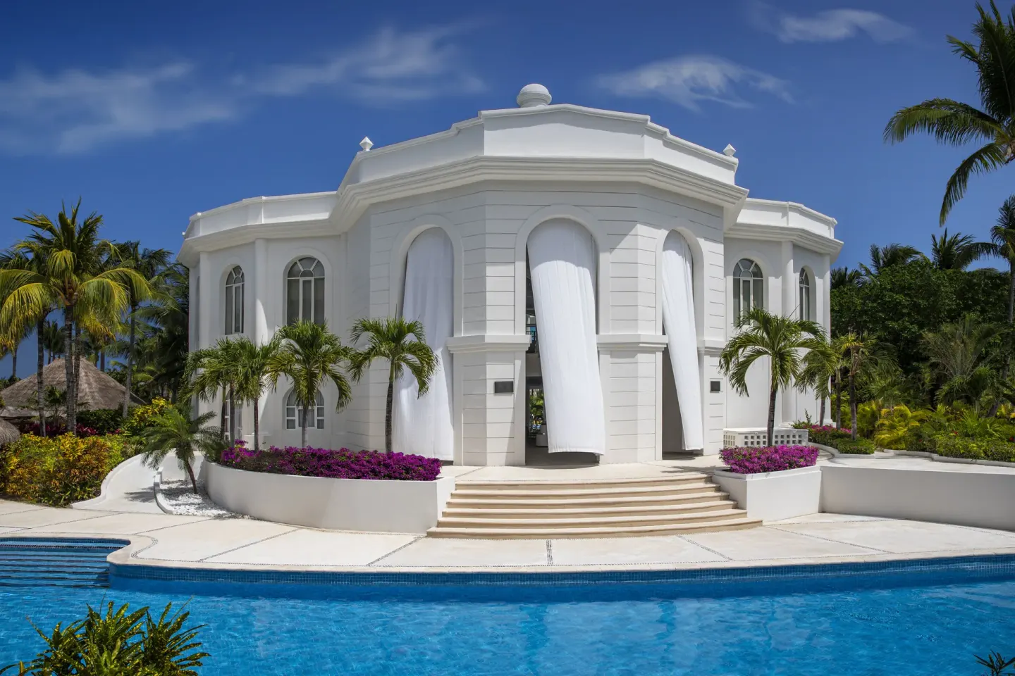 White resort building beside a pool at Excellence Riviera Cancun.