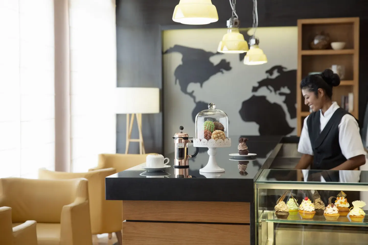 Coffee shop counter with pastries and a staff member at Excellence Riviera Cancun.