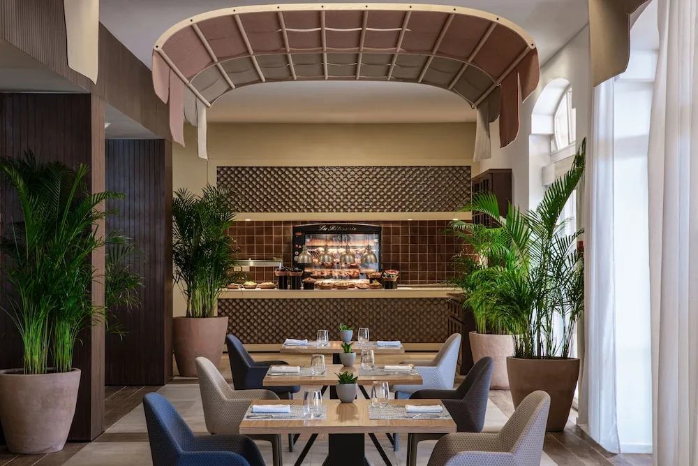 Restaurant dining room with buffet display and potted palms at Excellence Riviera Cancun.