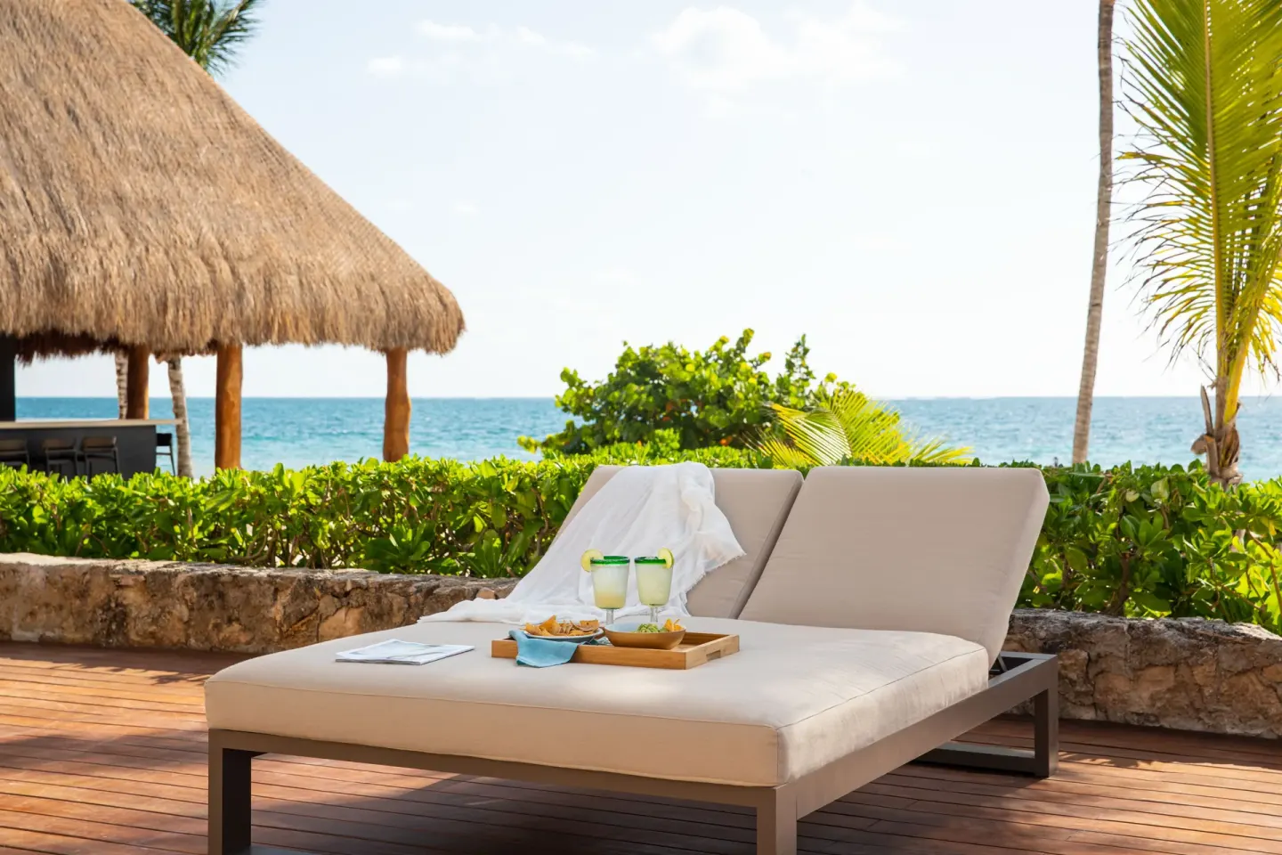 Padded double lounger on a wooden terrace by the ocean at Excellence Riviera Cancun.
