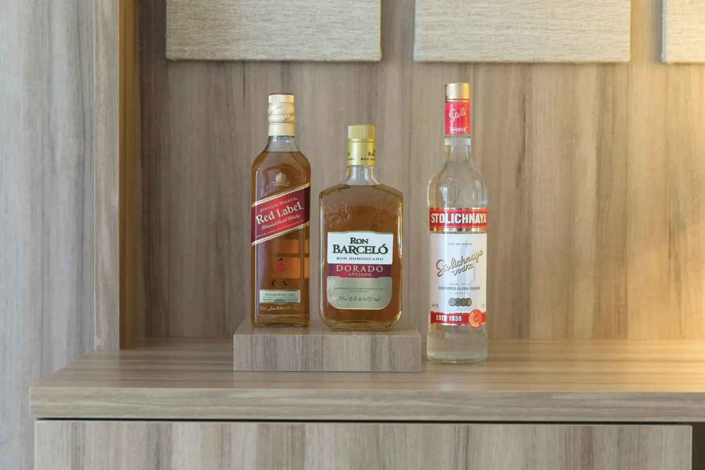 In-room liquor bottles on a wood shelf in a suite at Excellence Riviera Cancun.
