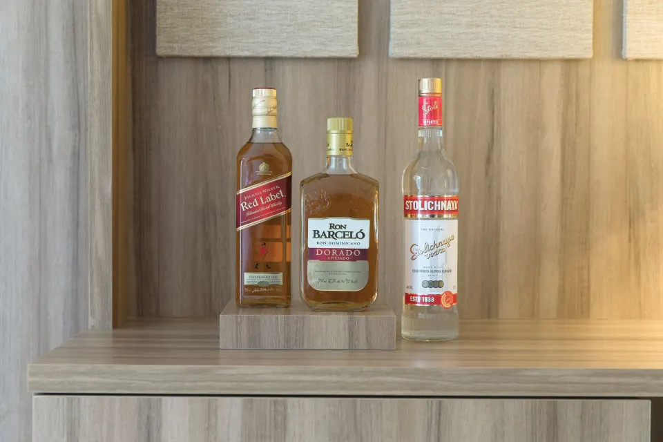In-room liquor bottles on a wood shelf in a suite at Excellence Riviera Cancun.