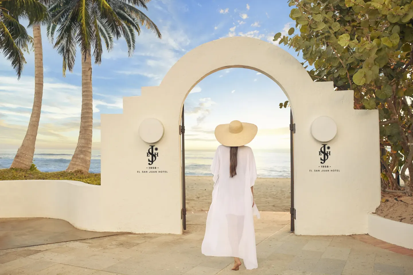Guest walking through an arched beach gate at Fairmont El San Juan.