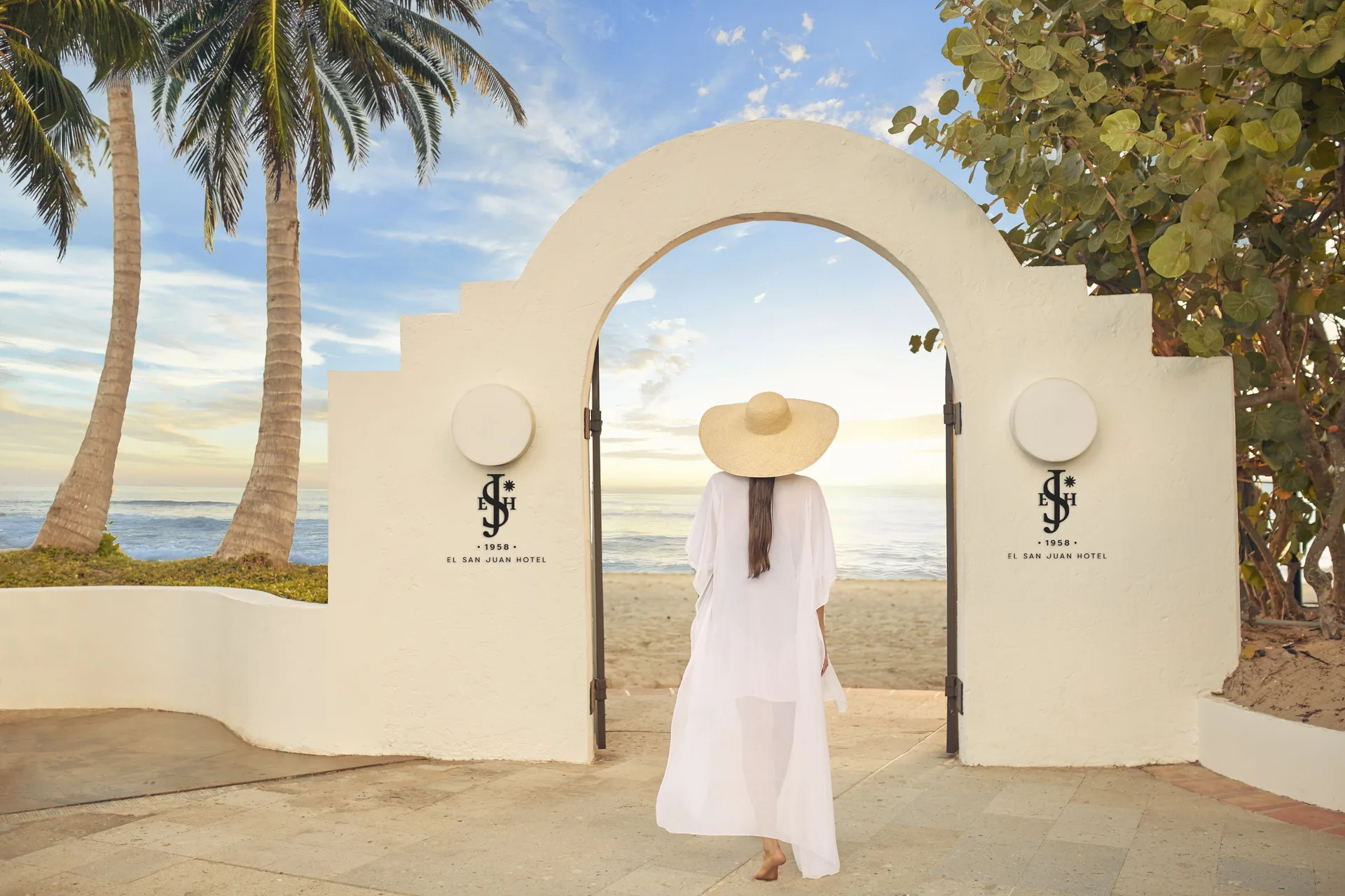Guest walking through an arched beach gate at Fairmont El San Juan.