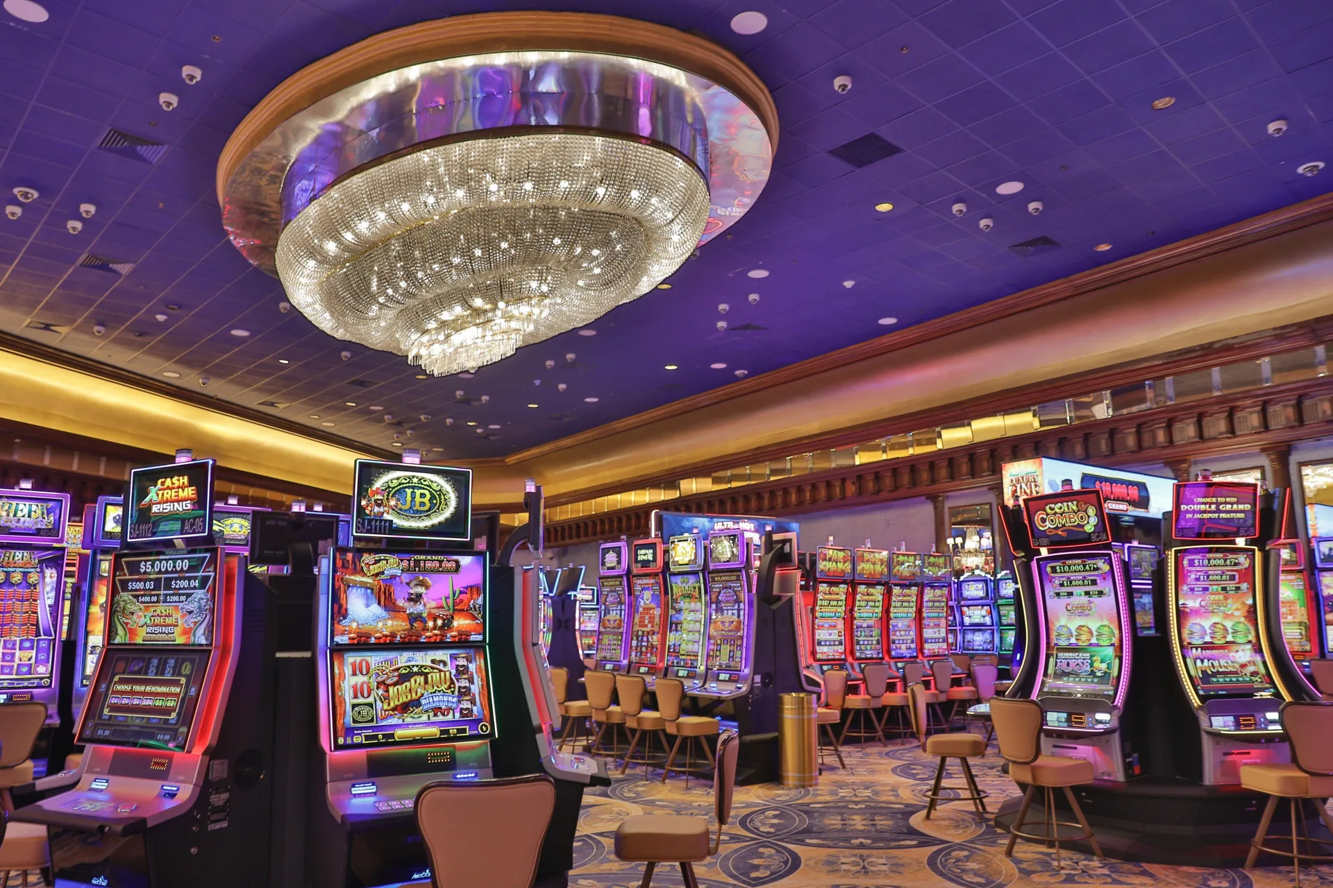 Rows of colorful slot machines beneath a large ceiling light at Fairmont El San Juan.