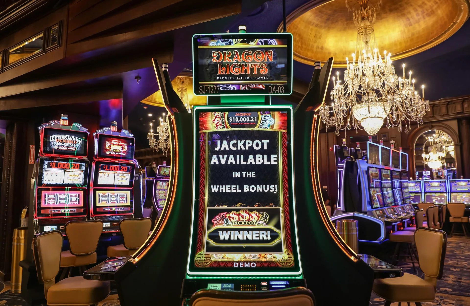 A tall slot machine with chandeliers and more casino games at Fairmont El San Juan.