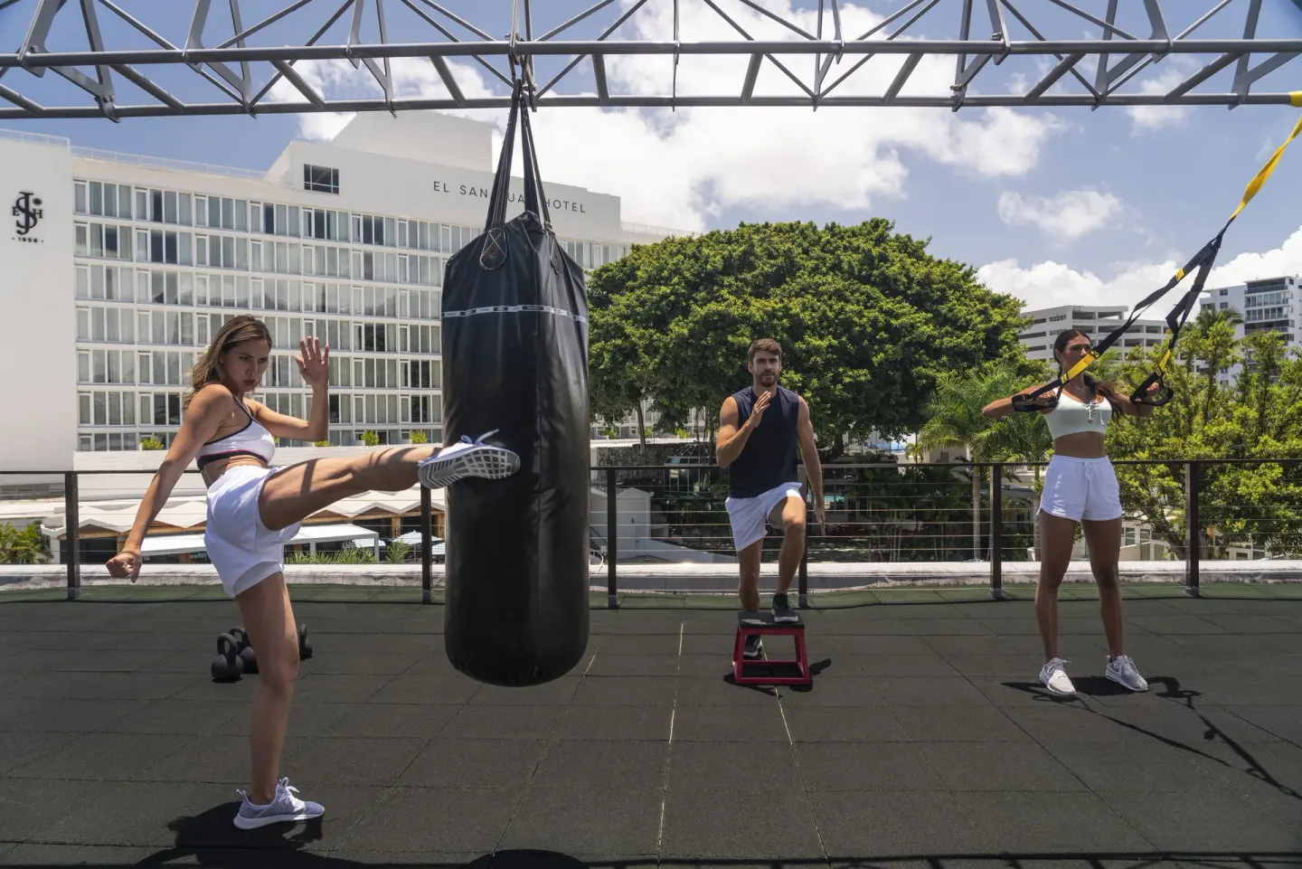Guests exercise with a punching bag and suspension straps at Fairmont El San Juan.