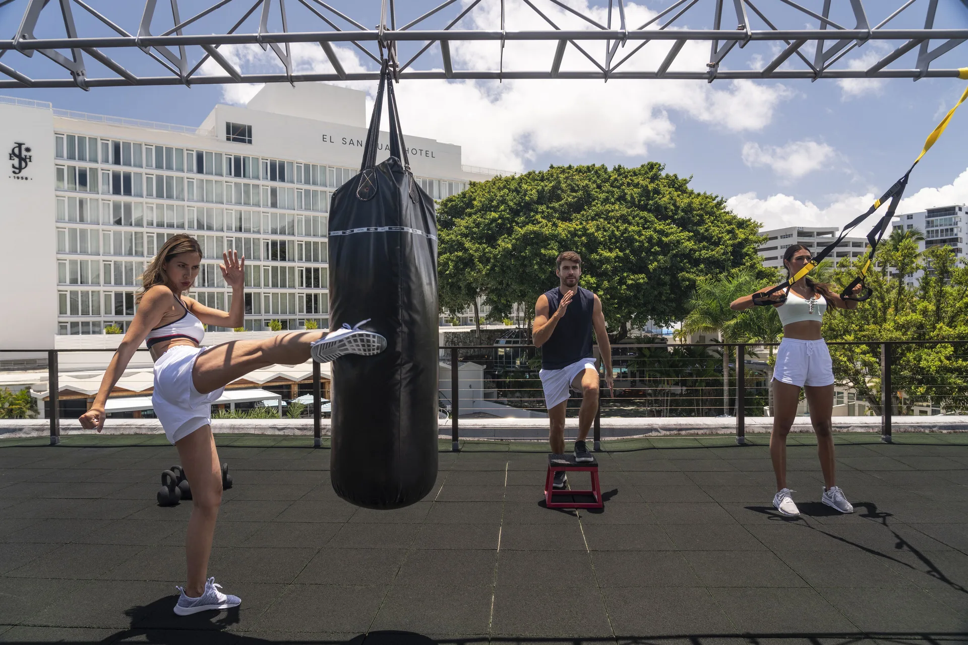 Guests exercise with a punching bag and suspension straps at Fairmont El San Juan.