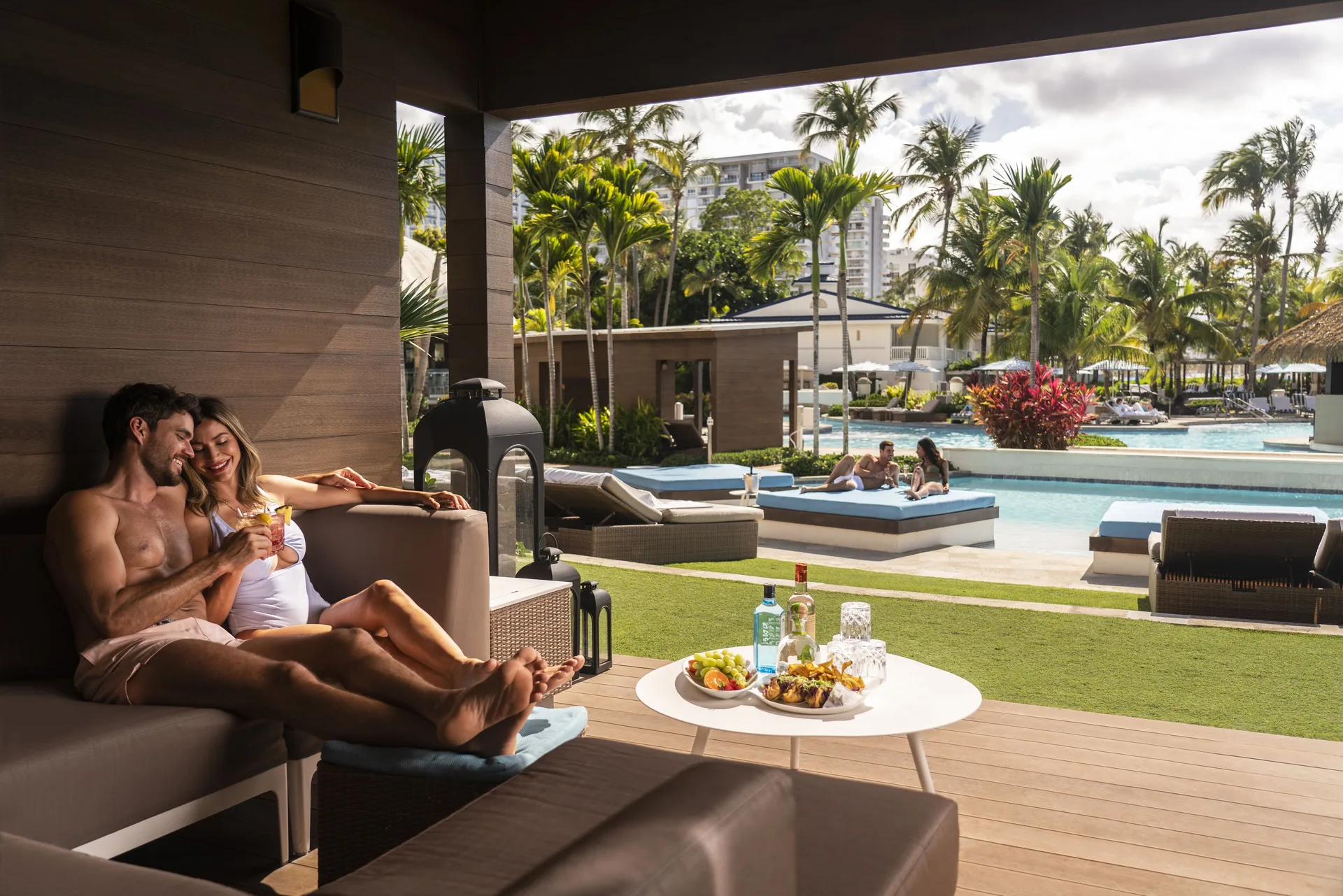 Couple lounging in a poolside cabana with drinks at Fairmont El San Juan.