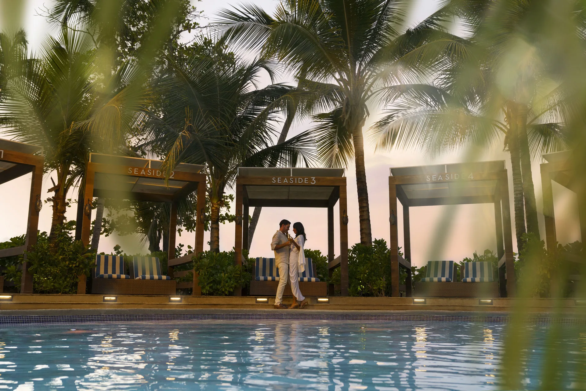 Seaside cabanas glow beside the pool at sunset at Fairmont El San Juan.
