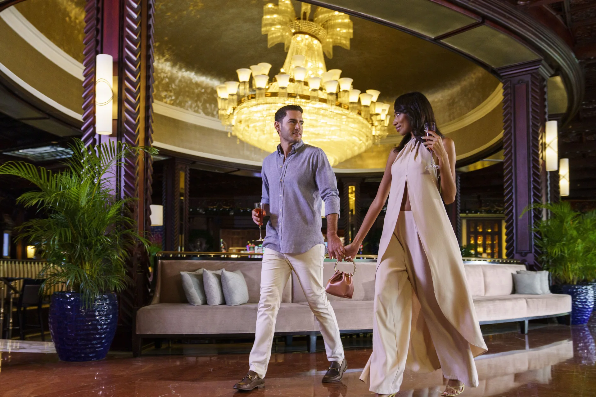 Couple with drinks beneath the chandelier in The Lobby at Fairmont El San Juan.
