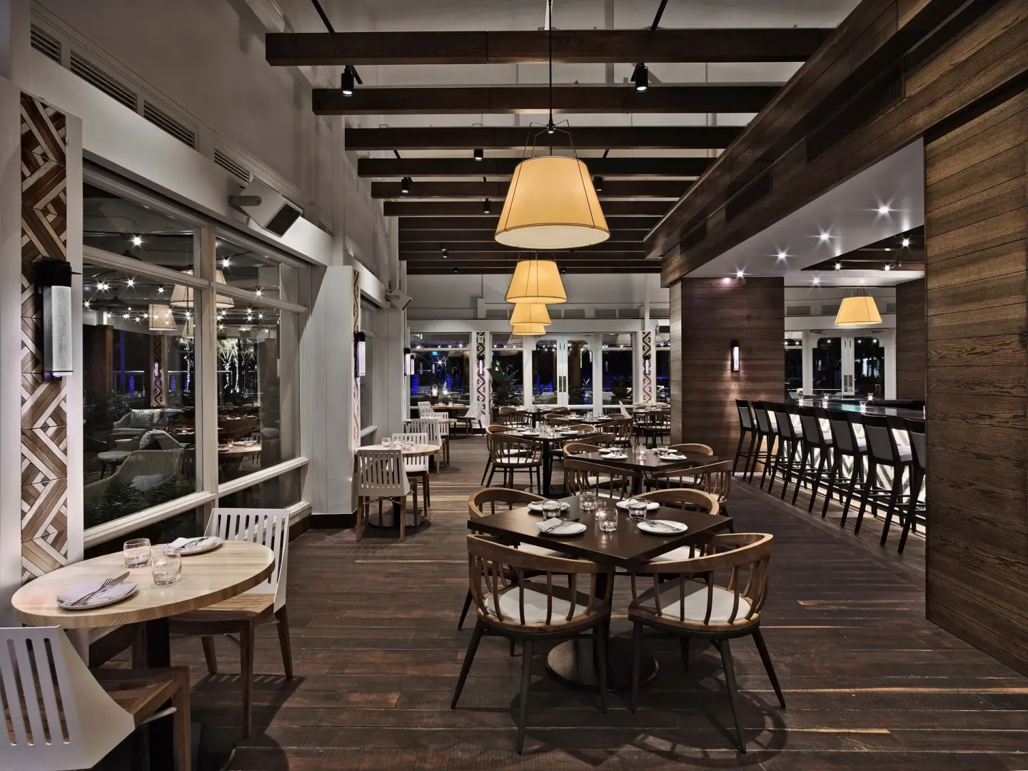 Dining room with wood floors, round tables, and a bar at Fairmont El San Juan.