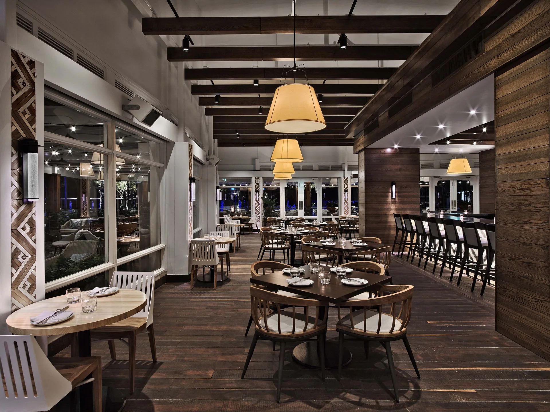 Dining room with wood floors, round tables, and a bar at Fairmont El San Juan.