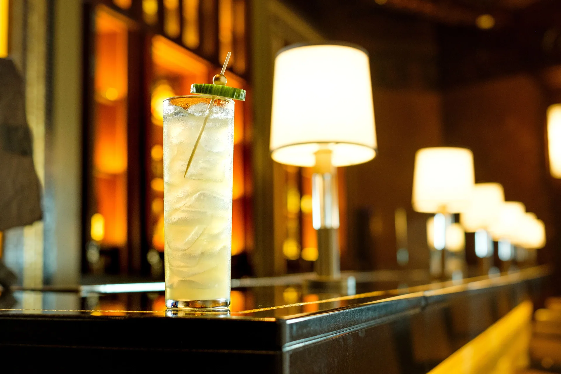 Tall iced cocktail on a lamp-lit bar at Fairmont El San Juan.
