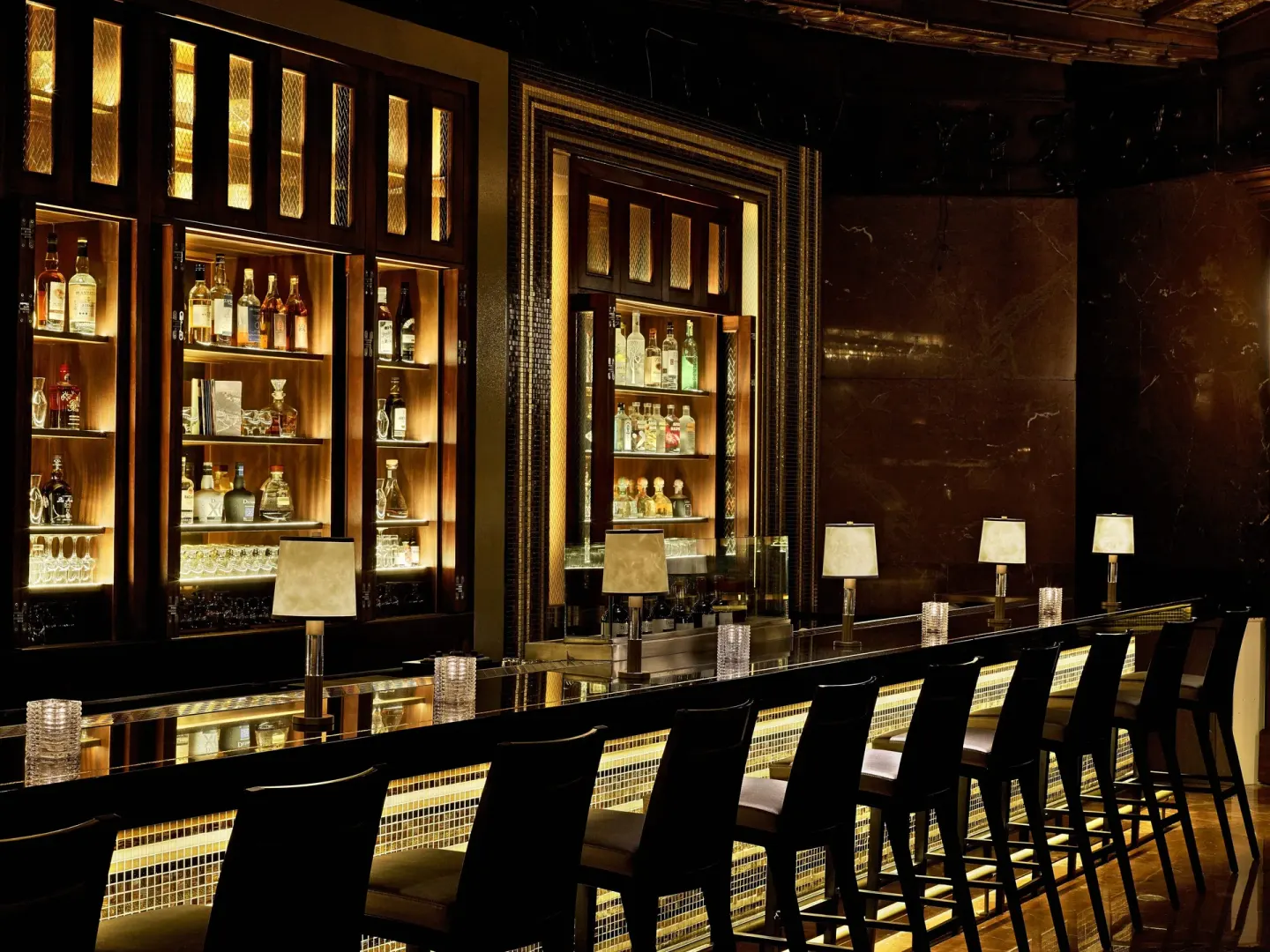 Backlit bottle shelves and bar seating at Fairmont El San Juan.