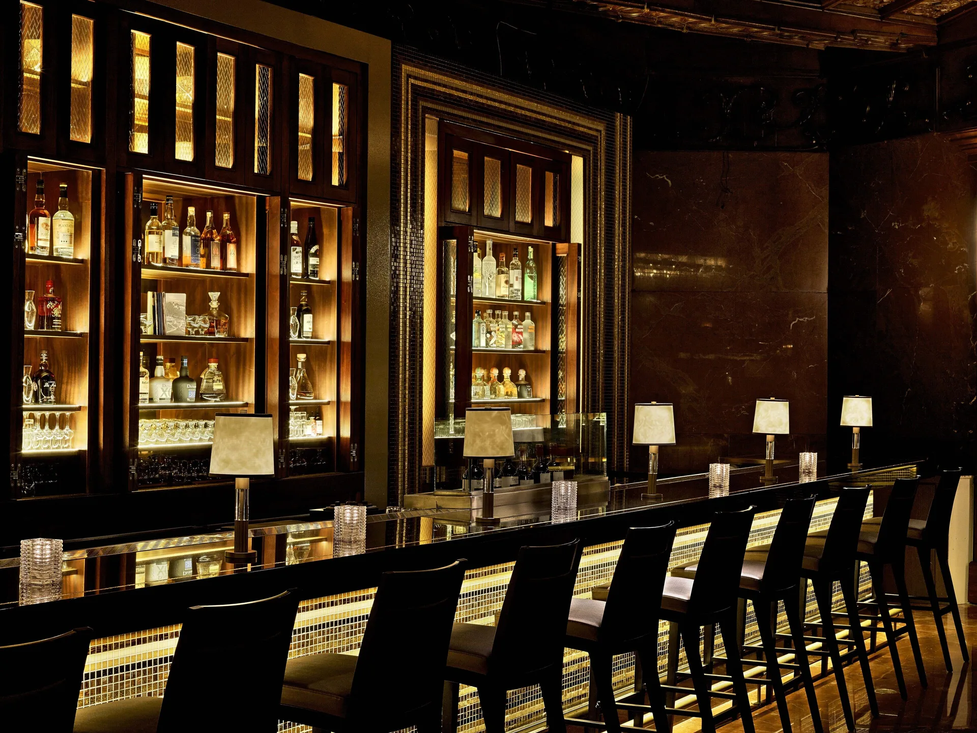 Backlit bottle shelves and bar seating at Fairmont El San Juan.