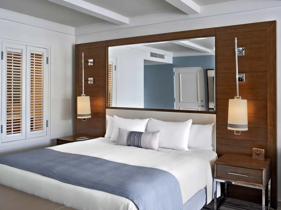 King bed with wood headboard wall in a villa ocean view room at Fairmont El San Juan.