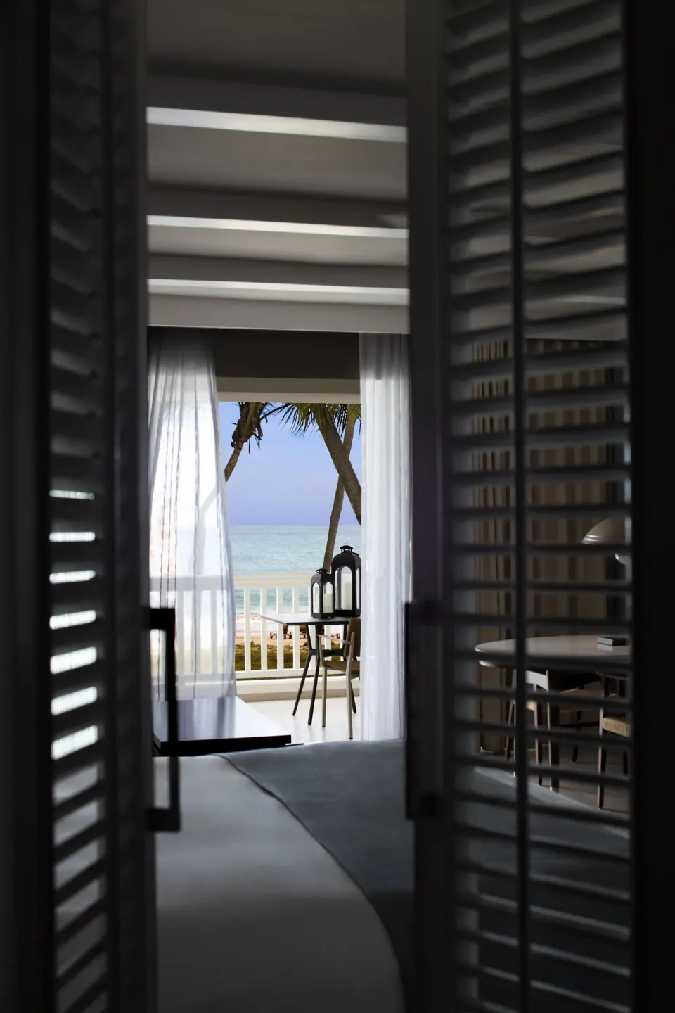 Villa room view through shutters to a balcony and ocean at Fairmont El San Juan.
