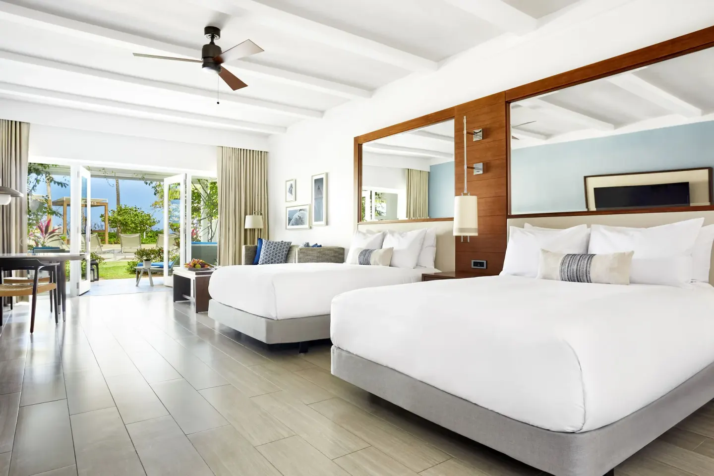 Two queen beds in a beachside villa room at Fairmont El San Juan opening to a garden terrace.