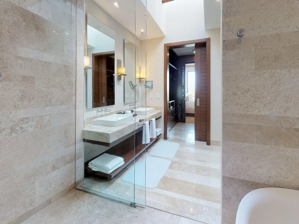 Bathroom with glass shower, vanity, and soaking tub at Fairmont Heritage Place Mayakoba.