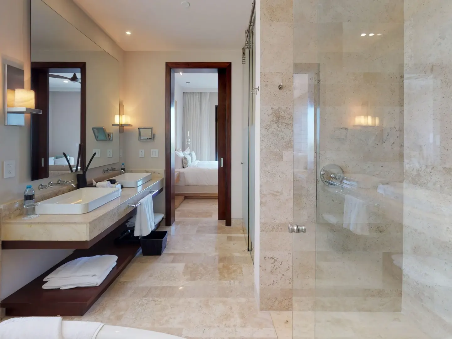 Stone bathroom with double vanity and glass shower at Fairmont Heritage Place Mayakoba.