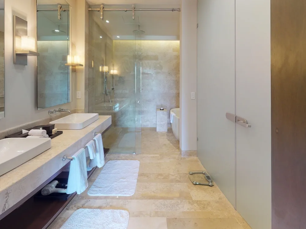 Bathroom with twin sinks and glass shower at Fairmont Heritage Place Mayakoba.