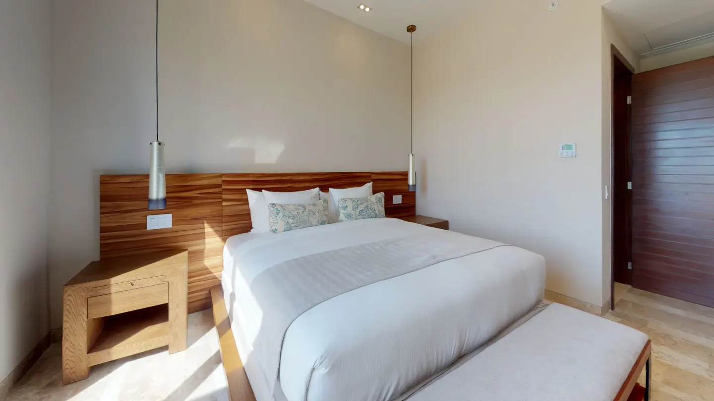 King bedroom with wood headboard at Fairmont Heritage Place Mayakoba.