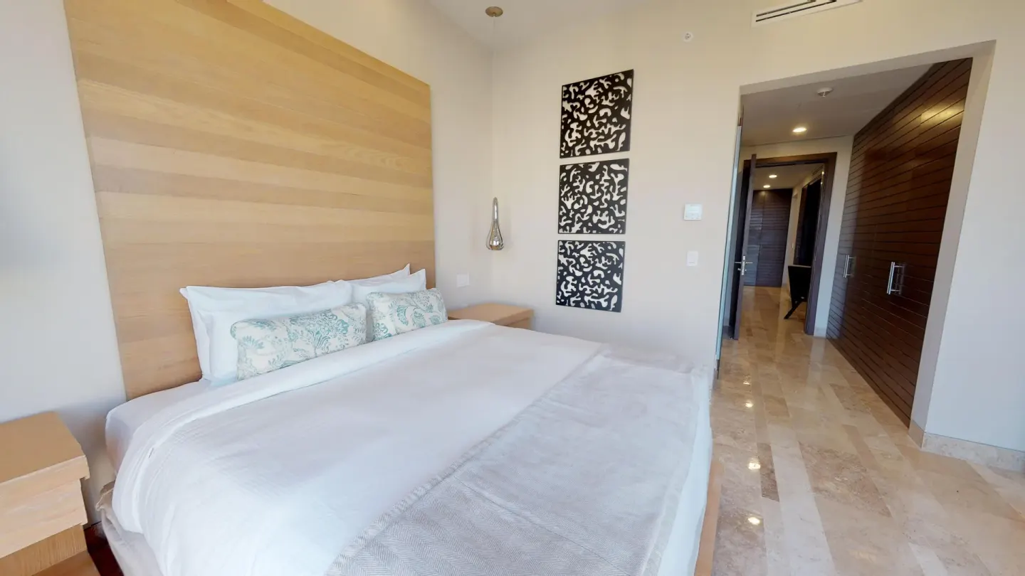 King-bed guest room with hallway and decorative wall panels at Fairmont Heritage Place Mayakoba.