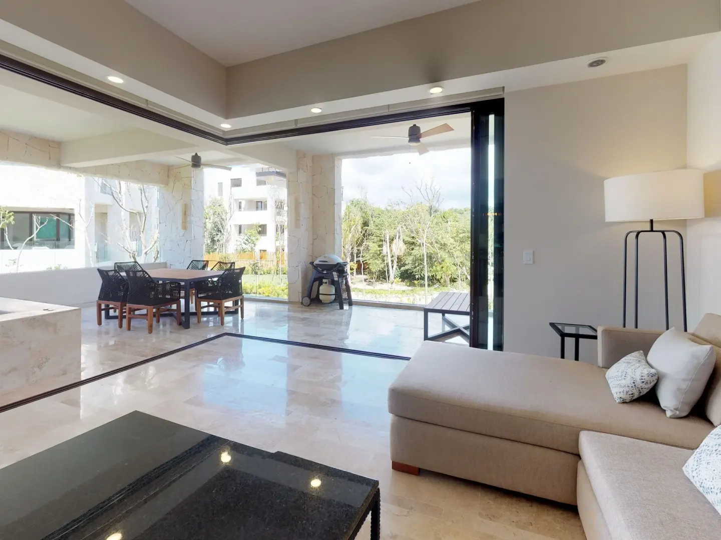 Living area with sectional sofa opening to a covered terrace at Fairmont Heritage Place Mayakoba.