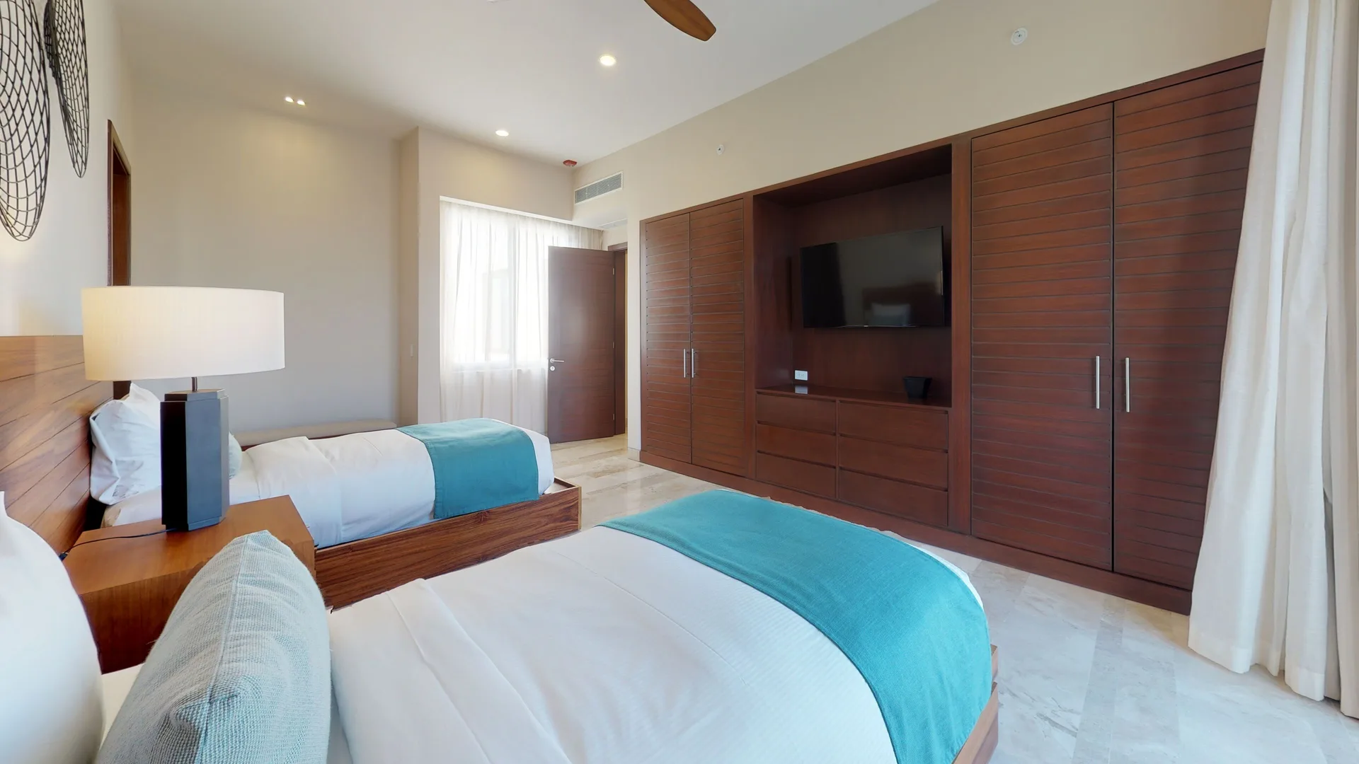 Twin-bed guest room with built-in wood wardrobe and TV at Fairmont Heritage Place Mayakoba.