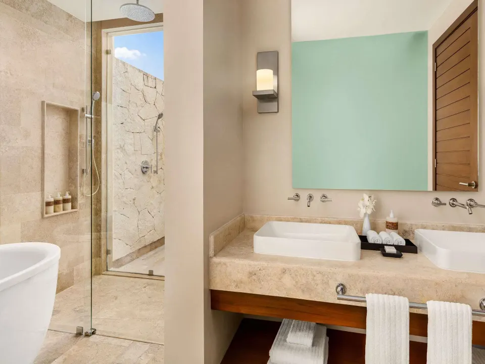 Bathroom with double vanity and glass shower at Fairmont Heritage Place Mayakoba.