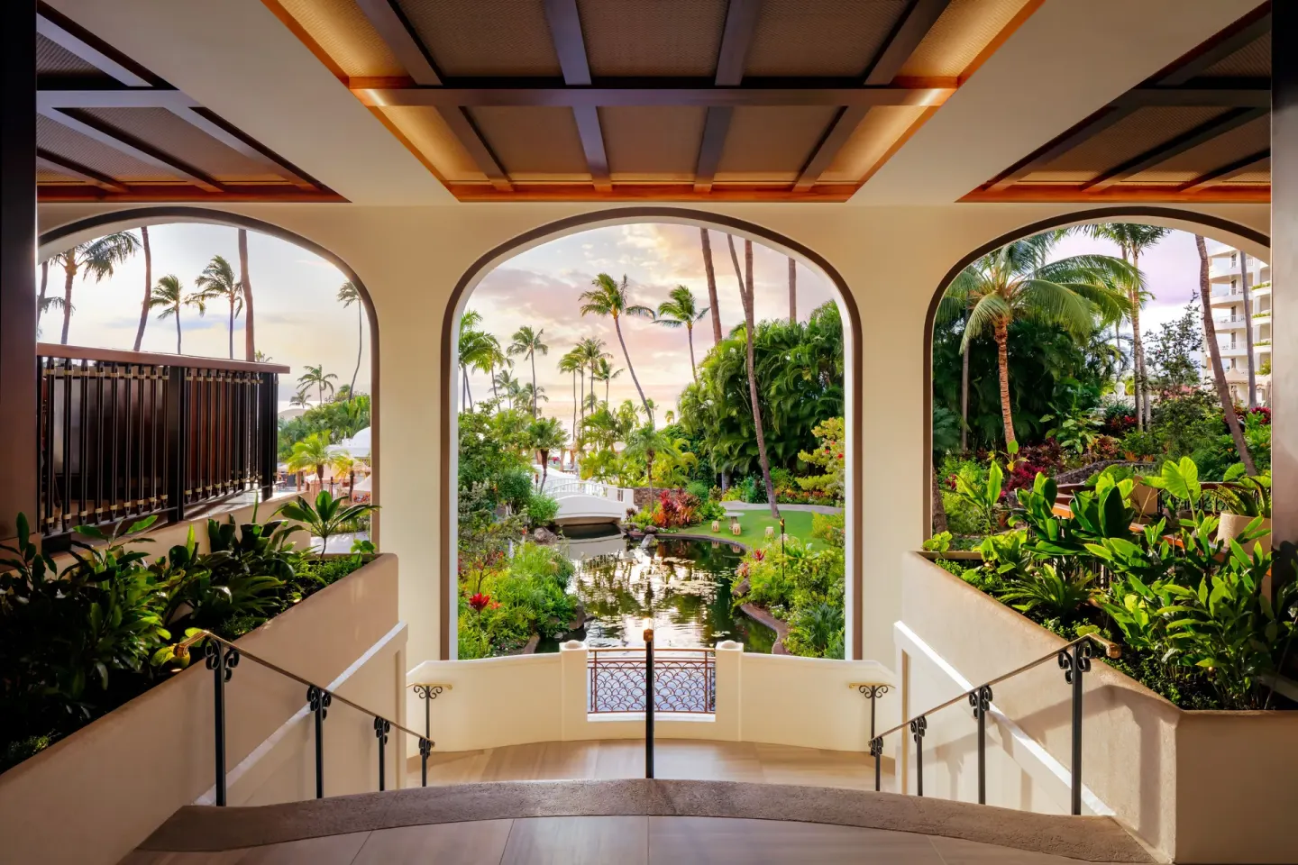Arched walkway overlooking tropical gardens and a pond at Fairmont Kea Lani Maui.