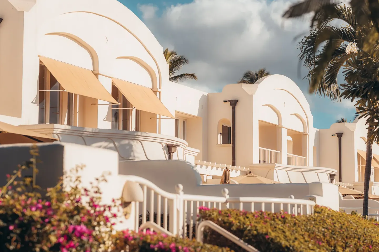 White arched resort buildings with awnings and flowers at Fairmont Kea Lani Maui.
