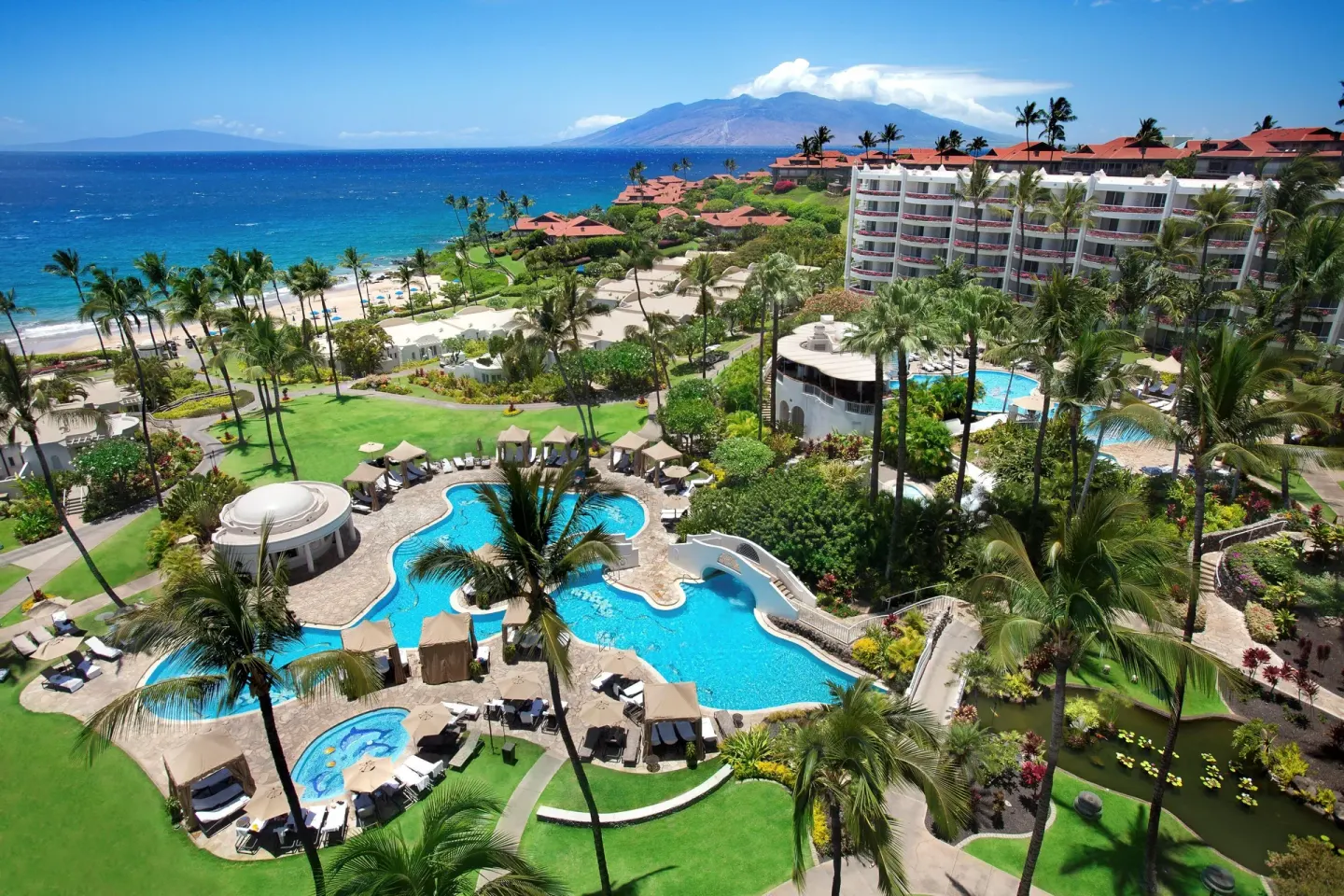 Daytime view of pools, palms, lawns, beach, and ocean at Fairmont Kea Lani Maui.