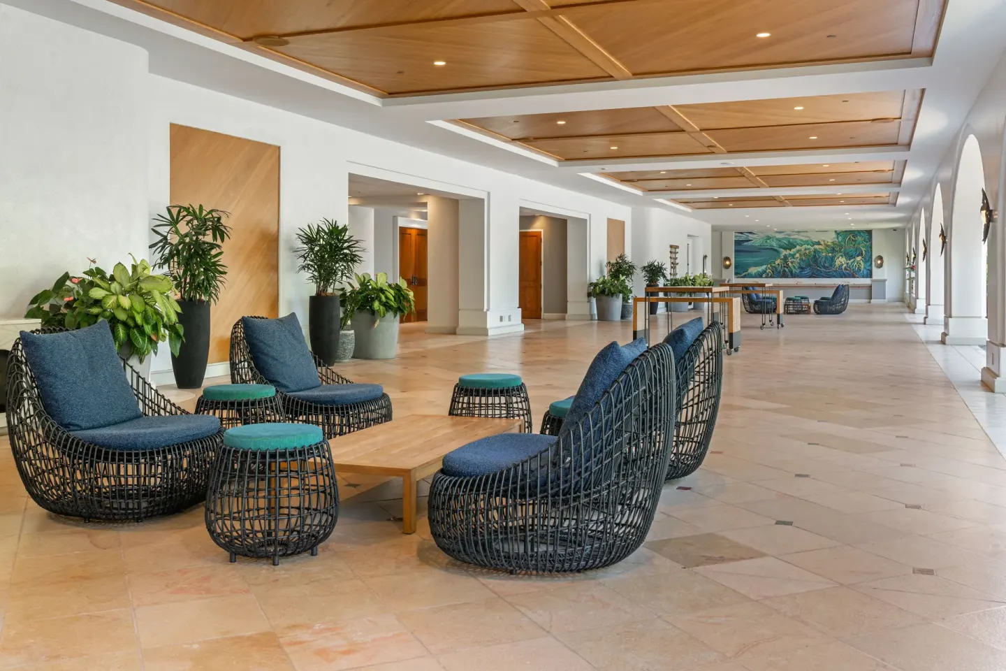Open lounge corridor with woven chairs and plants at Fairmont Kea Lani Maui.
