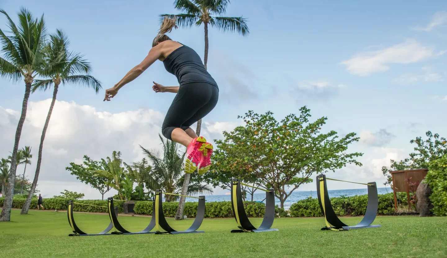 A person jumps over outdoor fitness obstacles at Fairmont Kea Lani Maui.