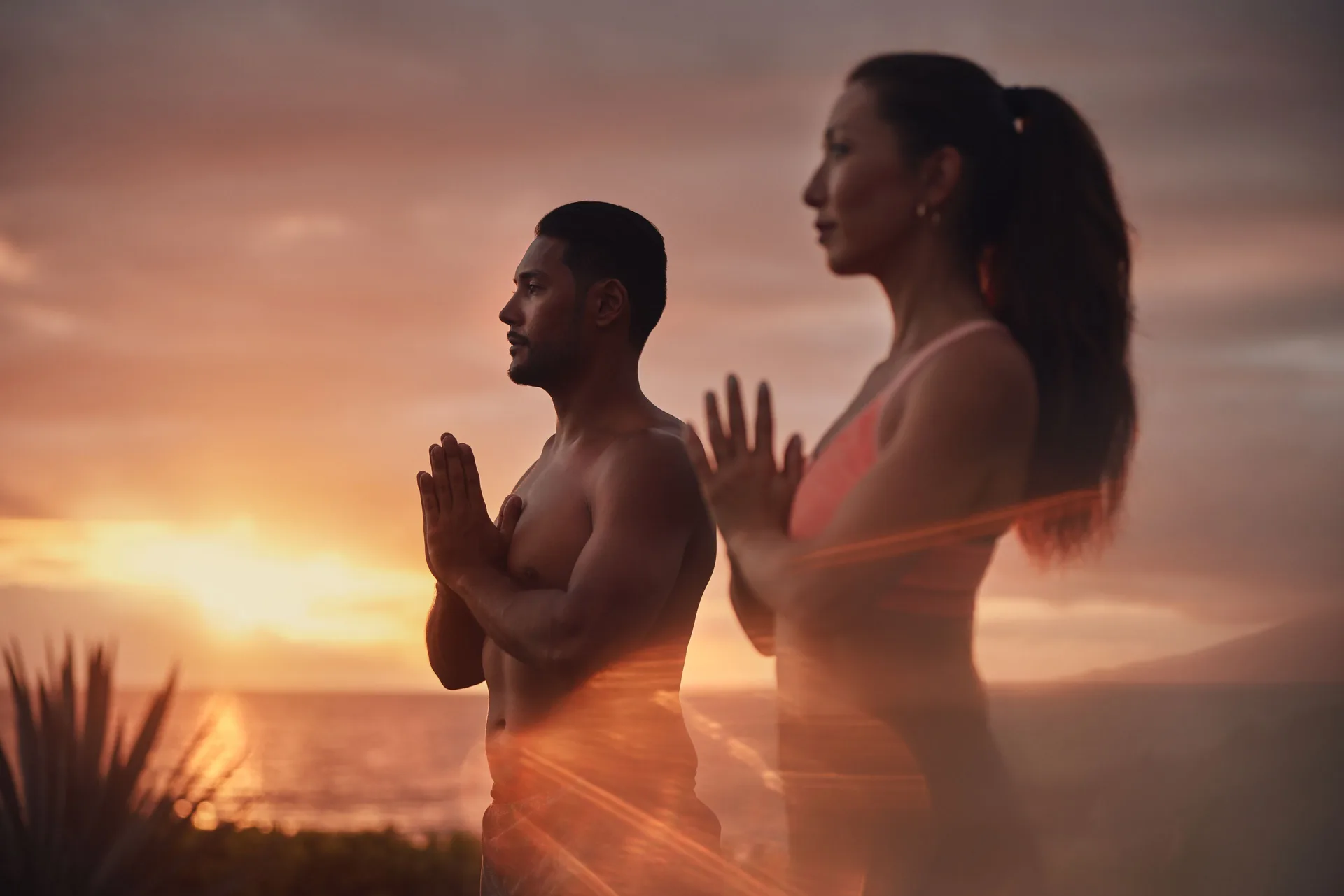 Two people practice yoga at sunset by the ocean at Fairmont Kea Lani Maui.