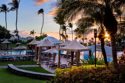 Pool cabanas and palm trees at sunset at Fairmont Kea Lani Maui.