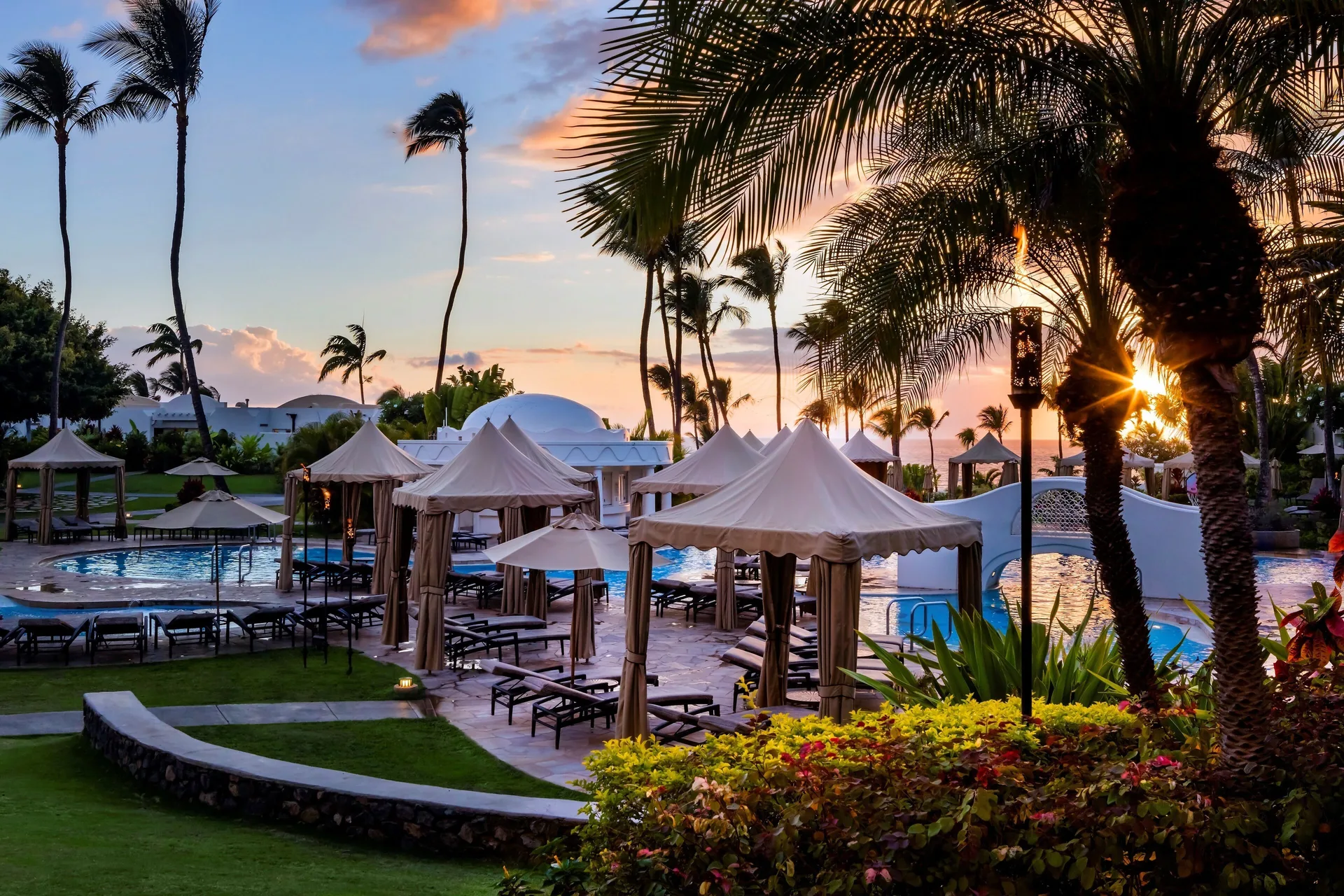 Pool cabanas and palm trees at sunset at Fairmont Kea Lani Maui.