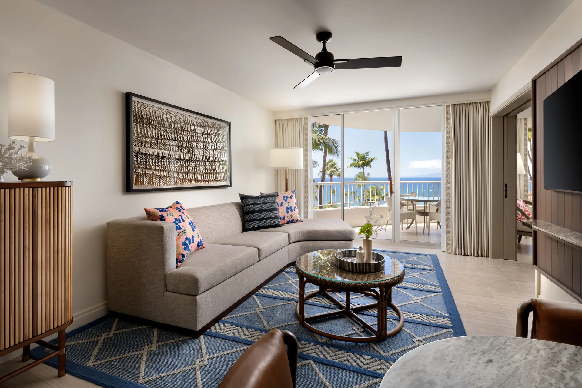 Living room in a Deluxe Ocean View Suite at Fairmont Kea Lani Maui with balcony and ocean beyond.