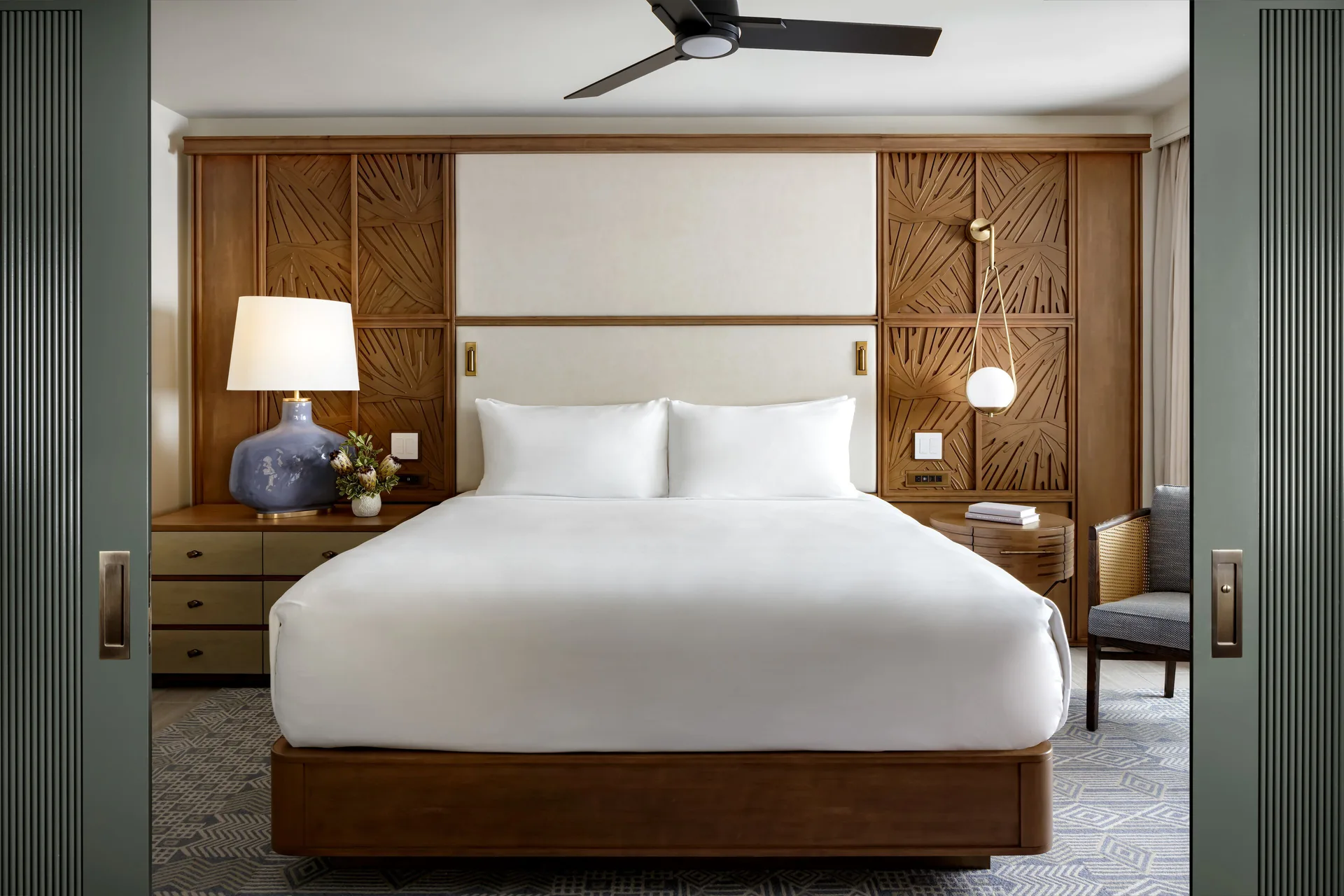 Kilohana Corner Suite king bed with carved wood panels at Fairmont Kea Lani Maui.