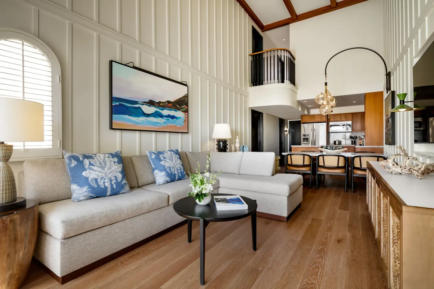 Luxury villa living room at Fairmont Kea Lani Maui with sectional sofa, kitchen, and loft railing.