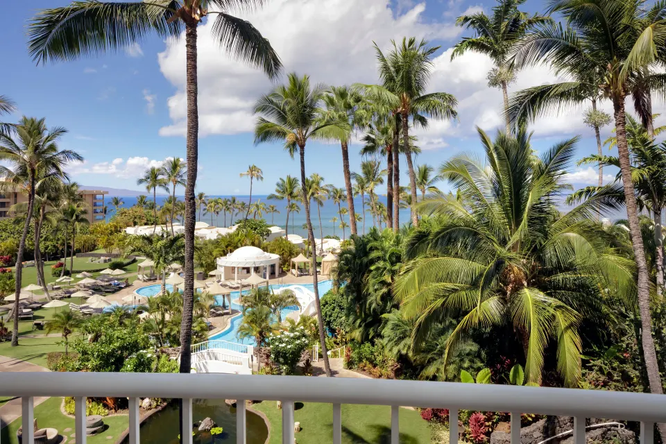 Ocean View Suite balcony view with palms, pools, and ocean at Fairmont Kea Lani Maui.