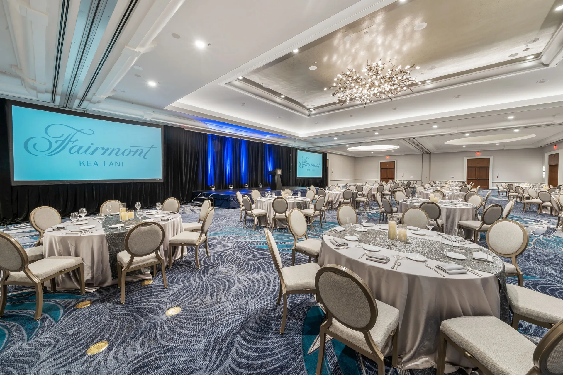 Ballroom set with round banquet tables and projection screens at Fairmont Kea Lani Maui.