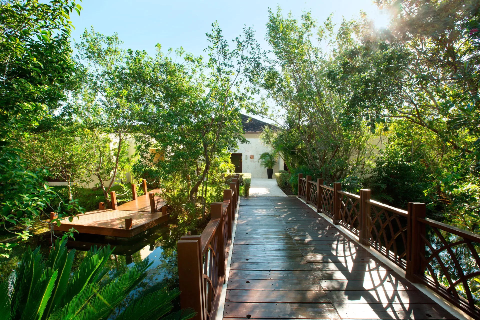 A wooden bridge crosses lush waterways and gardens at Fairmont Mayakoba.