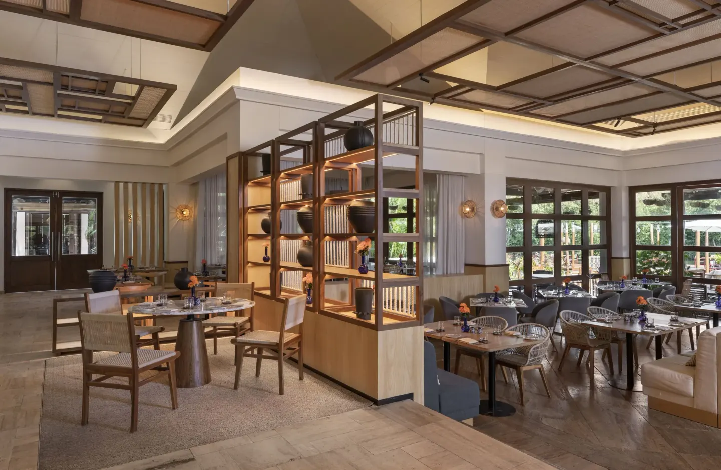 Spacious restaurant dining room with wood shelving and set tables at Fairmont Mayakoba.