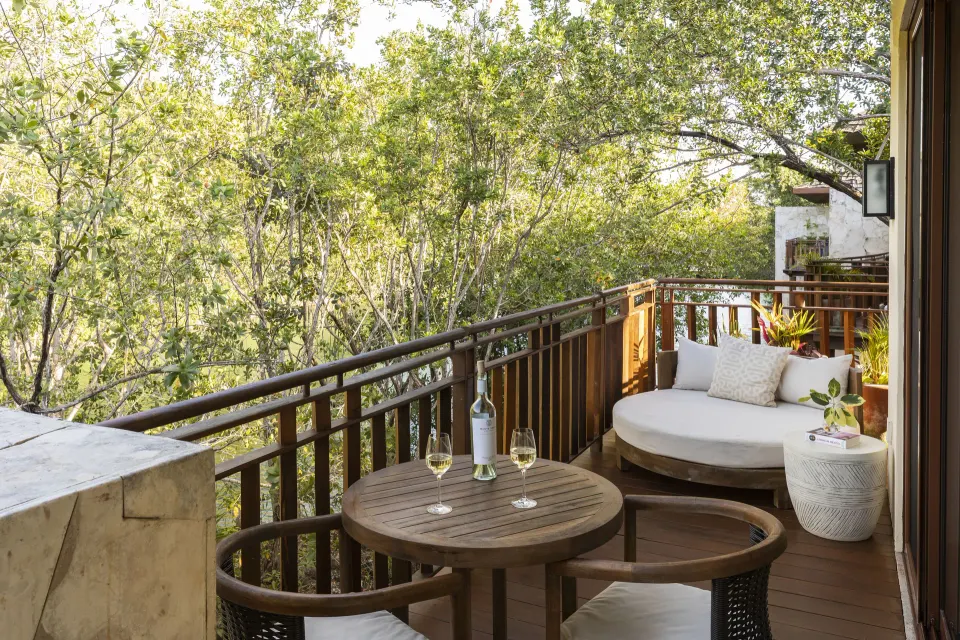 Casita Signature suite balcony with daybed and wooded view at Fairmont Mayakoba.
