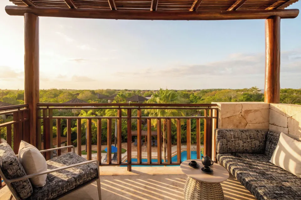 Fairmont Mayakoba balcony at Fairmont Mayakoba with cushioned seating, a small table, and treetop views.